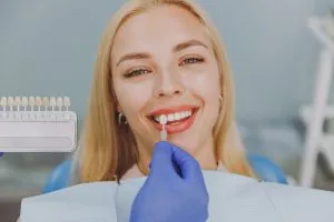 Woman with dental bib having teeth examined, dental tool and shade guide visible